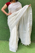 Off-white handloom linen saree with tassel border draped elegantly, showcasing natural texture and sheer fabric